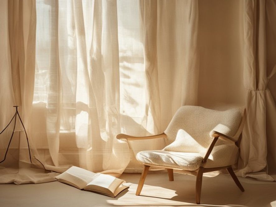 Soft afternoon light through linen curtains with open book on wooden chair